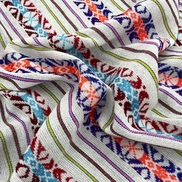 Tela cambaya blanca con bordados en tonos vivos y líneas artesanales coloridas