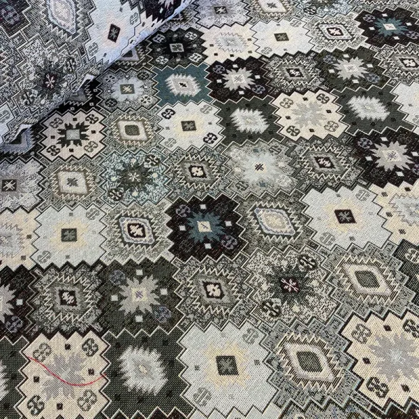 Tela gobelino gris con patrón geométrico artesanal en tonos fríos.