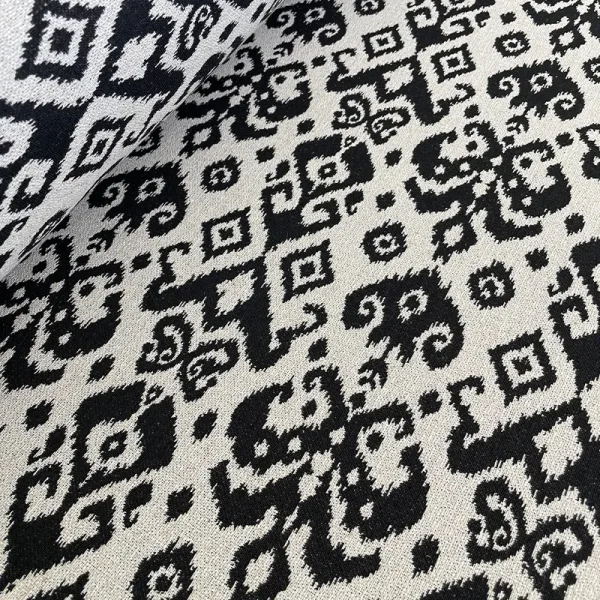 Tela con patrón de manchas negras estilo Rorschach sobre fondo crudo.