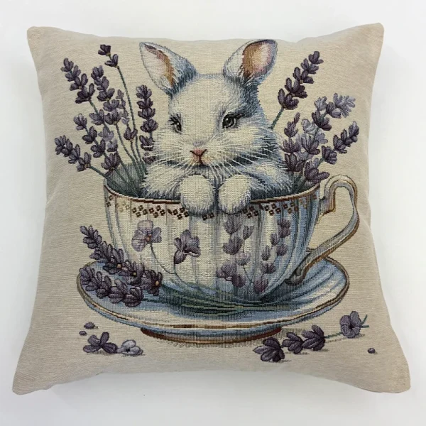 Funda de cojín de tela gobelino con dibujo de un conejo pequeño dentro de una taza de té rodeado de flores.
