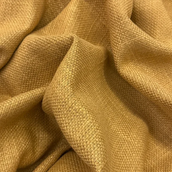 Primer plano de los pliegues de la Tela Siena en color camel, destacando su trama de tejido plano resistente y su textura natural de lino y algodón.