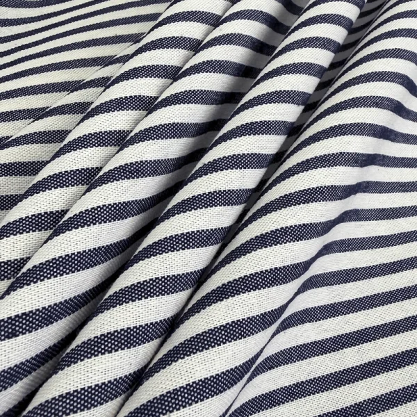 Detalle en primer plano de la Tela para tapizado Rigadim Líneas Marino mostrando su patrón simétrico de rayas azul marino sobre algodón y poliéster español.