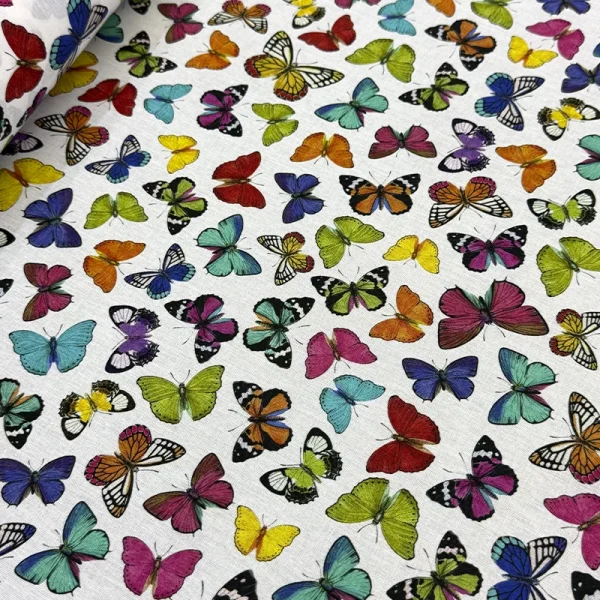 Tela Petite Mariposas Multicolores de la image_6c5e8a.jpg con estampado digital de mariposas de colores vivos sobre fondo blanco texturizado con efecto lino.