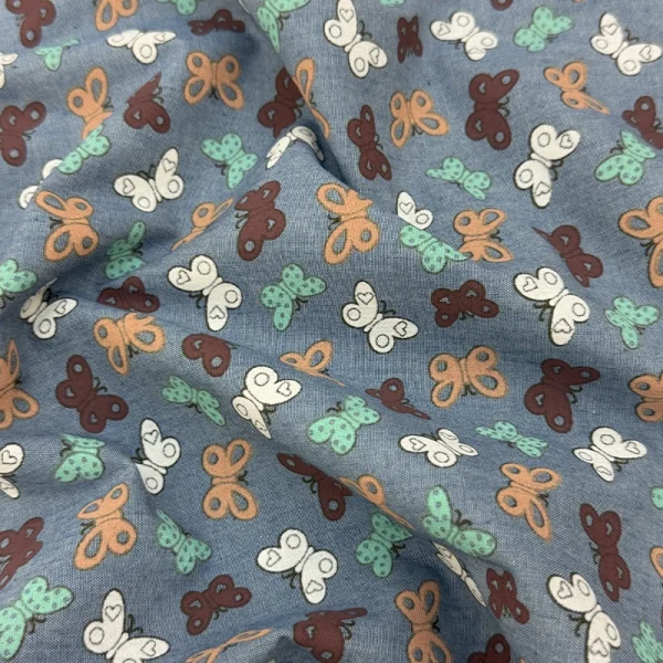 Polo Chambray Mariposas Multicolor con mariposas de colores sobre fondo azul.