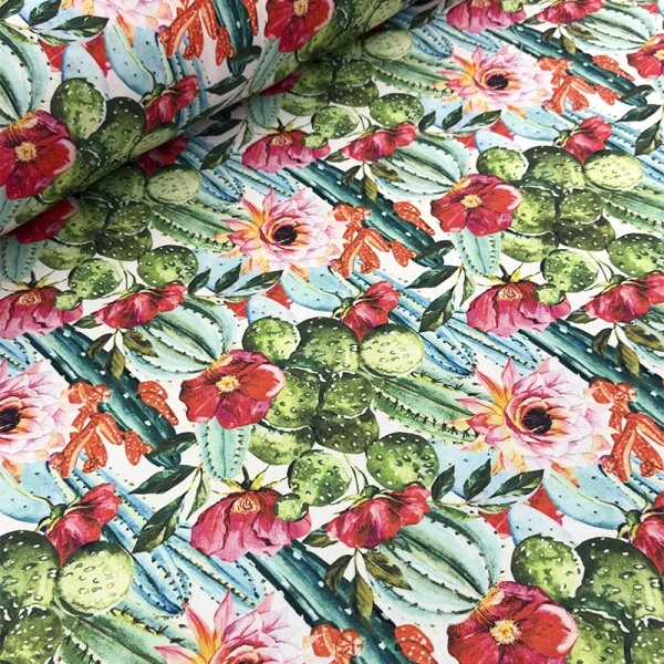 Tela mantelera Oasis Florido con estampado de cactus, nopales y flores en tonos verdes, rosas, rojos y blancos sobre fondo claro.